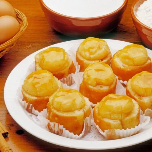 Traditional Santa Fe Piononos arranged on a white plate, showcasing their rolled sponge cake filled with yema (pastry cream) and topped with a caramelized crown.